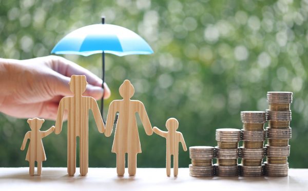 Protection,Model family with hand holding the umbrella and stack of coins money on natural green background, Finance insurance and Safe investment concept